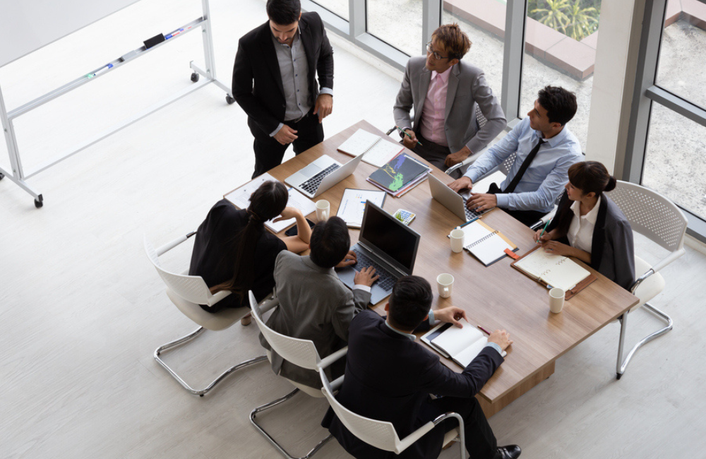 Top view of group of multiethnic busy people working in an office, Aerial view with businessman and businesswoman sitting around a conference table with blank copy space, Business meeting concept