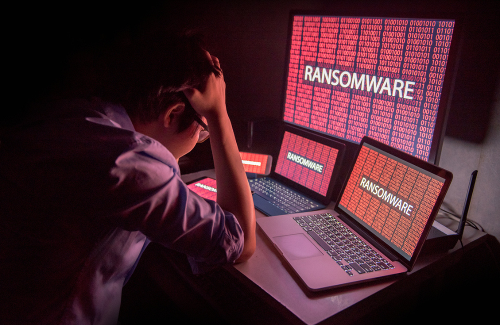 Young male frustrated, confused and headache by ransomware attack on desktop screen, notebook and smartphone, cyber attack and internet security concepts