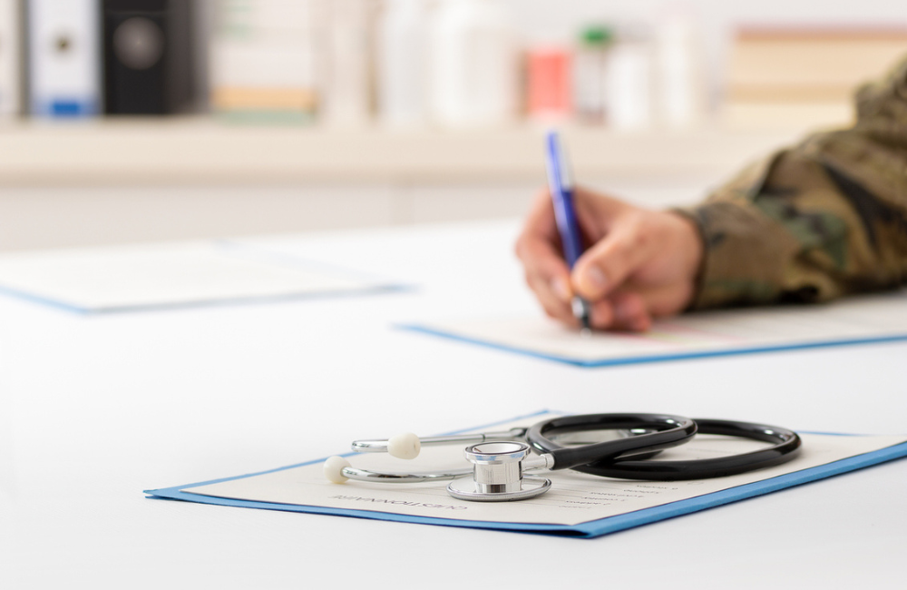 Cropped shot of a army doctor filling out paperwork in a hospital.