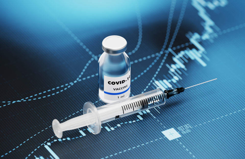 COVID-19 vaccine and syringe sitting over blue financial graph background. Selective focus. Horizontal composition with copy space. COVID-19 Vaccine and Stock market and finance concept.