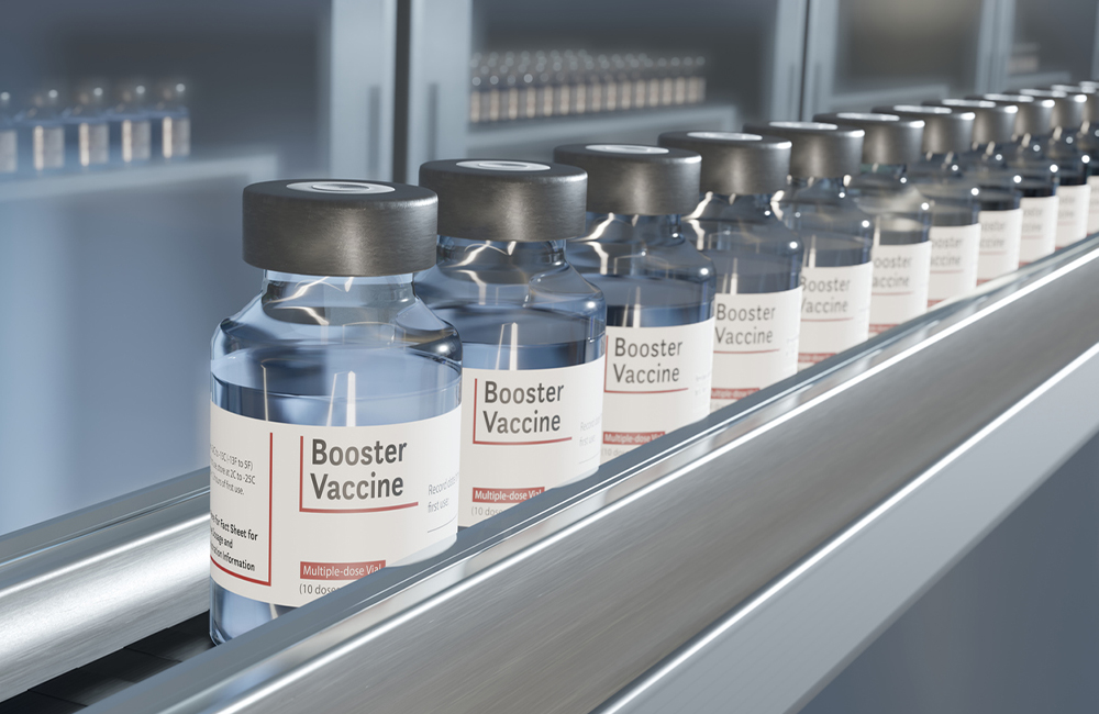 Multiple vials in a row on a conveyor belt in a pharmaceutical factory. There are additional supplies in storage cabinets in the background.