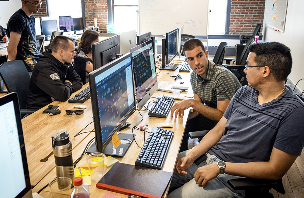 image of Staff Sgt. Jamie Benites, product manager, and Maj. Drew Armstrong, right, a data scientist, discuss a software development project at the office of Kessel Run, a program within the Defense Innovation Unit Experimental, a United States Department of Defense organization, in Boston May. 30, 2018.
