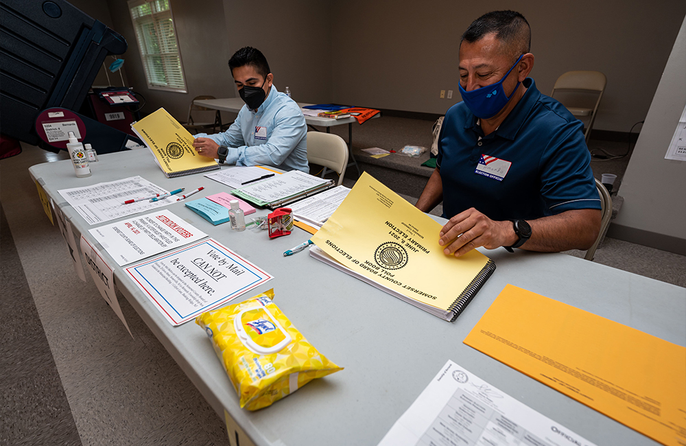 image of two people with masks masks working at a voter registration table during the covid-19 pandemic