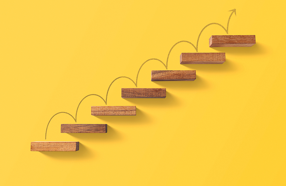 image of Wooden blocks arranged in a shape of staircase on yellow background.