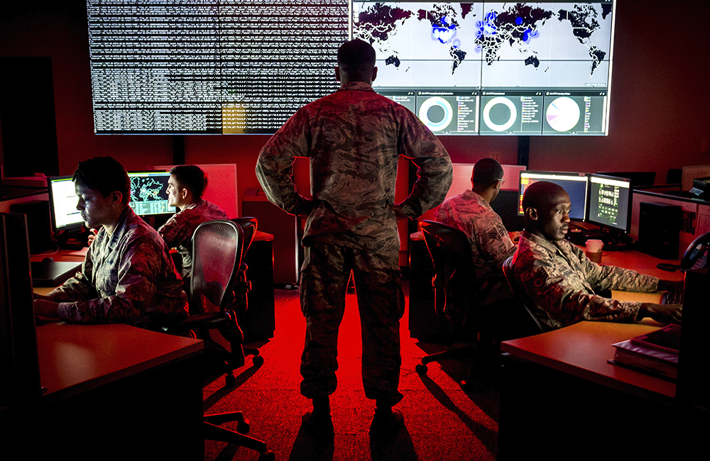 image of Capt. Taiwan Veney, cyber warfare operations officer, watches members of the 175th Cyberspace Operations Group, in the Hunter's Den at Warfield Air National Guard Base, Middle River, Md.