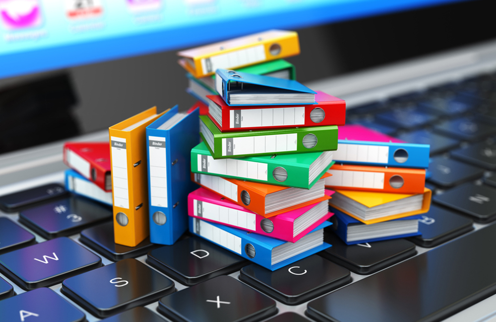 conceptual 3d illustration of a stack of small books sitting on top of laptop keyboard representing how the government is beginning to adopt ai tools to expedite its obligation of records transparency.