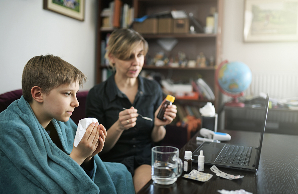 Little boy aged 10 is having a cold. During the COVID-19 pandemic is it risky to visit doctor in a regular way. Mother are using telemedicine video call to consult the doctor about the boy's illness. Nikon D850