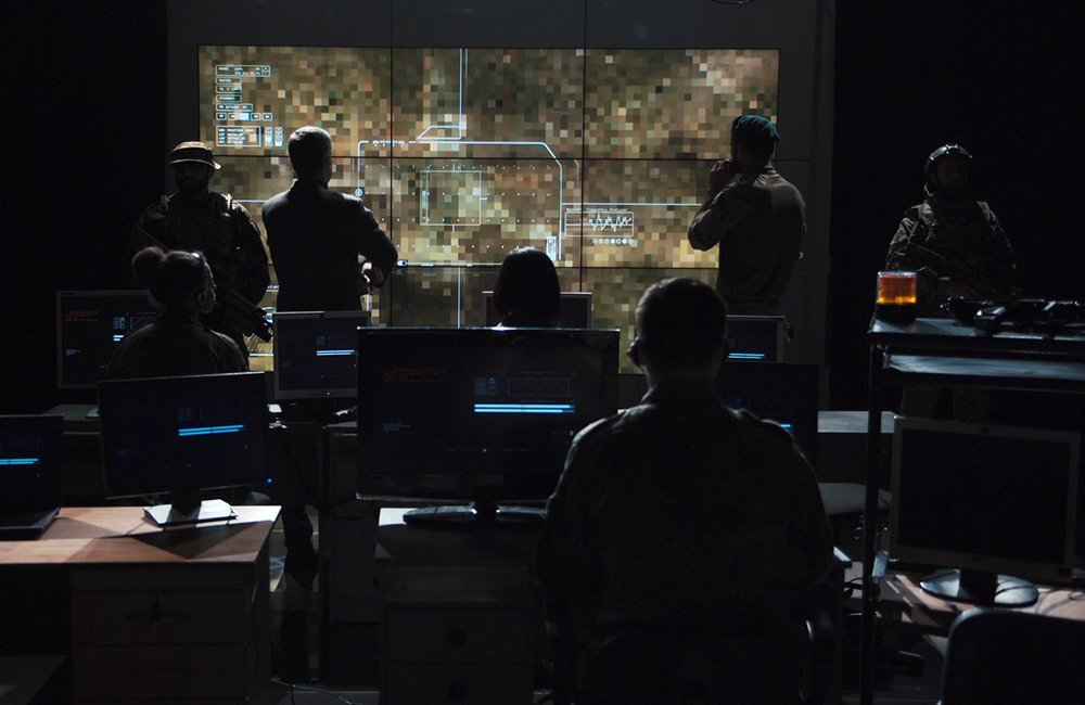 Group of soldiers or spies in dark room with large monitors and advanced satellite communication technology launching a missle. Includes flashing yellow light.